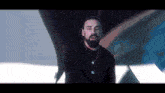 a man with a beard is wearing a black sweater