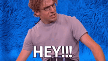 a man wearing glasses and a purple shirt says hey