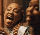 two women are laughing with their tongues out and one of them is holding a glass .