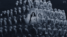 a black and white photo of a woman standing in front of a crowd of people