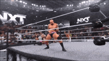 a wrestler in a ring with nxt written on the wall