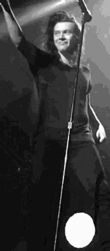 a black and white photo of a man singing into a microphone .
