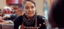 a woman in a plaid apron is sitting at a table and talking to another woman .