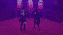 two women are dancing in a dark room with a purple light behind them