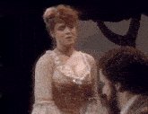 a woman with red hair is standing in front of a man with a beard