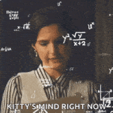 a woman is standing in front of a blackboard with mathematical equations on it .