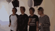 a group of young men are standing next to each other with balloons in the air .