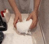 a person is holding a piece of white paper on a table next to a tape dispenser