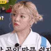 a woman with blonde hair is wearing a white shirt and making a funny face .