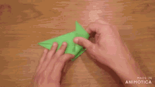 a person is holding a green origami piece that was made in animotica