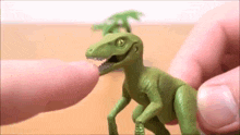a person is touching a toy dinosaur with their fingers