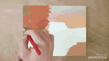 a person is painting on a piece of paper that says made in animatica on it