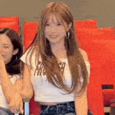 a woman wearing a white crop top with the word pro on it sits next to another woman