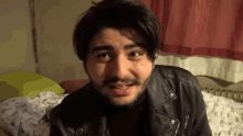 a young man with a beard wearing a leather jacket