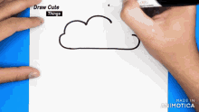 a person is drawing a cloud with a marker on a piece of paper