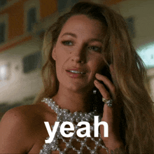 a woman wearing a pearl necklace is talking on a cell phone and the word yeah is above her head