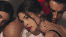 a woman with red lipstick and a red rose in her hair looks at the camera