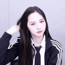 a girl with long black hair is wearing a black adidas jacket and tie