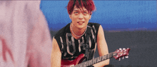 a young man with red hair is playing a guitar and wearing a black shirt that says j-pop