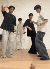 a group of young men are dancing on a wood floor