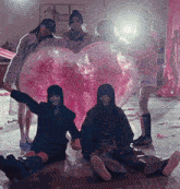 a group of people posing for a picture with a large pink heart shaped balloon