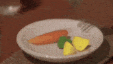 a white plate topped with a carrot , green pepper , and yellow slices of lemon .