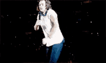 a man in a white shirt is singing into a microphone on a stage