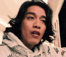 a close up of a man 's face with a hoodie that has dinosaurs on it
