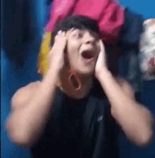 a man is holding his hands to his ears and making a funny face with his mouth open .