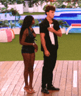 a man and a woman standing on a deck with their hands on their hearts
