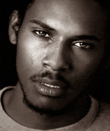 a black and white photo of a man with a tear running down his face