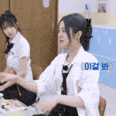 a woman in a white shirt and tie is sitting in a classroom with korean writing on the wall behind her