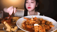 a woman is eating a plate of food with chopsticks .