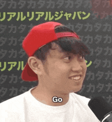 a young man wearing a red hat and a white shirt with the word go on his neck