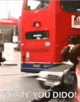 a woman taking a picture of a red double decker bus with the words " i hate you dido " below it
