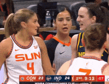 a female basketball player wearing a sun jersey talks to another player