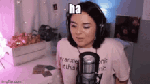 a woman wearing headphones is sitting in front of a microphone and making a funny face .