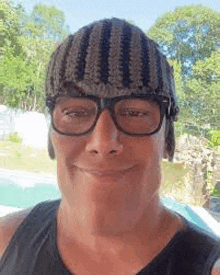 a man wearing a beanie and glasses is smiling .