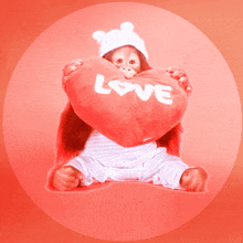 a baby monkey holding a heart shaped pillow that says love on it