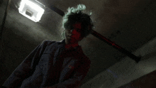a person with green hair is standing in a dark room with a light behind them