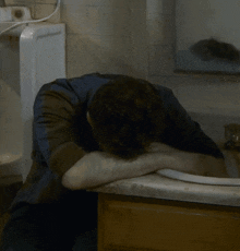 a man is laying his head on a sink