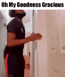 a man with a beard is standing in a hallway with the words oh my goodness gracious on the bottom
