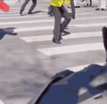 a man in a yellow vest is walking across a crosswalk