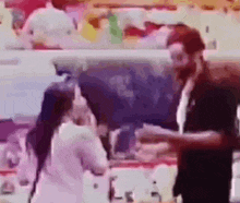 a man and a woman are talking to each other in a kitchen .