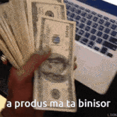 a person holding a bunch of money in front of a laptop