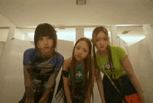 three girls are standing in a bathroom with one wearing a green shirt that says ' i am a girl ' on it