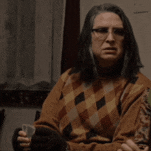 a woman wearing glasses and a plaid sweater holds a card