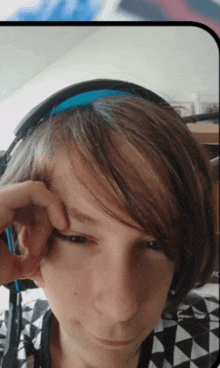 a young boy wearing headphones has his hand on his ear