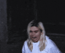 a woman wearing a white sweatshirt is screaming in the dark