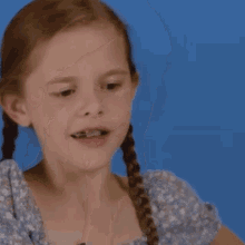 a little girl with pigtails and braces on her teeth is making a funny face .